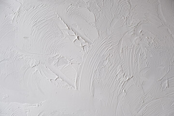 Applying decorative putty. White abstract texture of surface covered with putty. textured background of filler paste applied with putty knife in irregular dashes and strokes. Rough surface plaster - obrazy, fototapety, plakaty