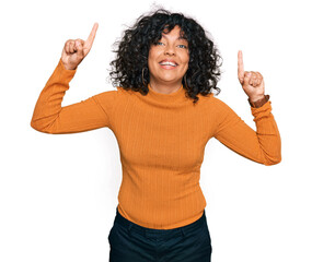 Young hispanic woman wearing casual clothes smiling amazed and surprised and pointing up with fingers and raised arms.
