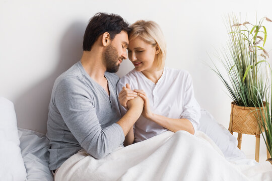 Image of closed eyes, hold hands man woman, leaning their heads on each other, married inlove lay couple at bedroom, praying in home bed. Prayers waiting child, pregnancy, problem issues, plea concept