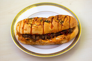 Delicious chicken hot dog with tomato sauce on a white plate on wooden background
