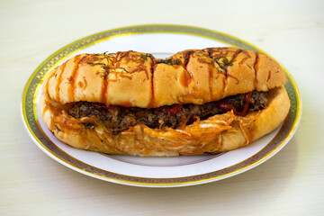 Delicious chicken hot dog with spicy tomato sauce on a white plate on wooden background