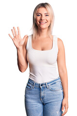 Young beautiful blonde woman wearing casual sleeveless t-shirt showing and pointing up with fingers number five while smiling confident and happy.
