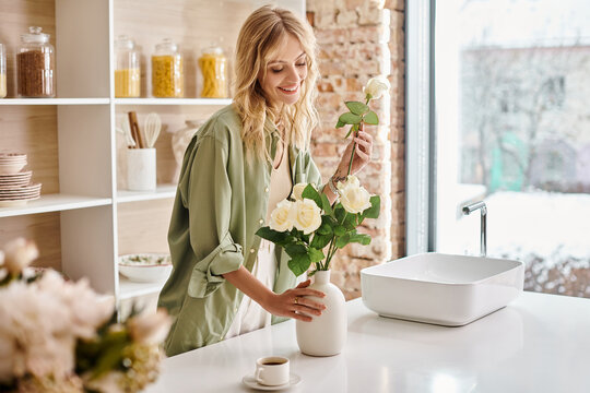 Woman in kitchen arranging colorful flowers in a vase at home.