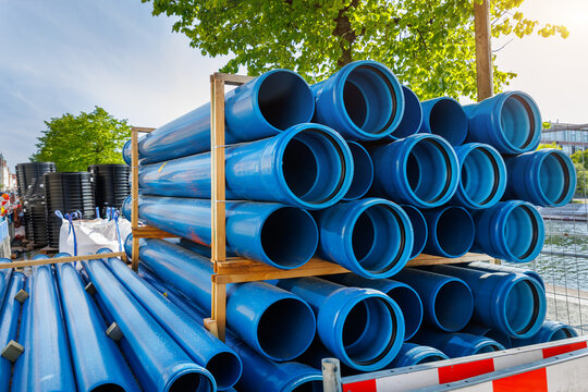 Close-up blue PVC plumbing pipes stacked wooden pallets replacement at german city street infrastructure construction site. Town development building industrial background