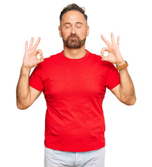 Handsome middle age man wearing casual red tshirt relax and smiling with eyes closed doing meditation gesture with fingers. yoga concept.
