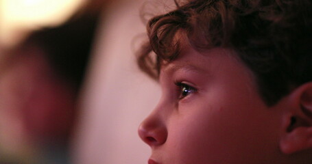 Young boy watching TV screen, casual candid child hypnotized by screen