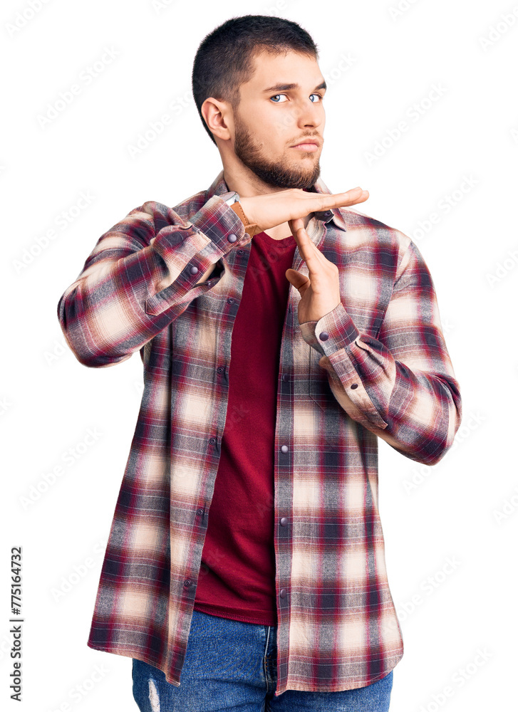 Sticker Young handsome man wearing casual shirt doing time out gesture with hands, frustrated and serious face