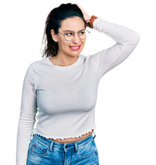 Young hispanic woman wearing casual clothes confuse and wonder about question. uncertain with...