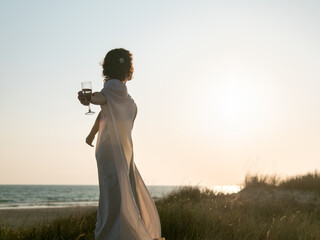 Elegant Figure Enjoying Wine at Beach Sunset