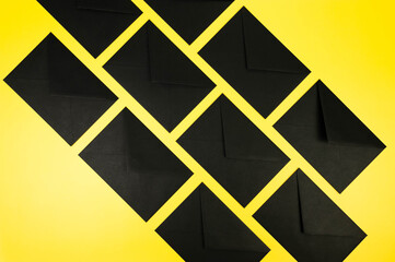 Top view of black envelopes on yellow background. Post flat lay. Copy space.