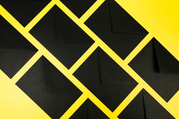 Top view of black envelopes on yellow background. Post flat lay. Copy space.