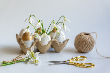Fototapeta na wymiar Minimal Easter concept. Festive spring mood, paper box with Easter eggs in light colors and snowdrop flowers.