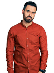 Young hispanic man with beard wearing casual shirt looking sleepy and tired, exhausted for fatigue and hangover, lazy eyes in the morning.