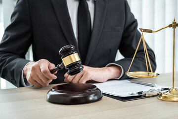 A male lawyer or notary working with contract papers, book and wooden gavel on table in courtroom, Law and Legal services concept - 775180519