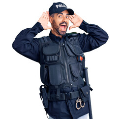 Young hispanic man wearing police uniform smiling cheerful playing peek a boo with hands showing face. surprised and exited