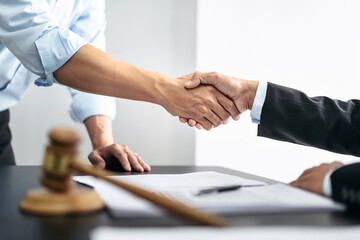 Handshake after good cooperation, Two people shaking hands after discussing contract agreement on front a judge's gavel - obrazy, fototapety, plakaty
