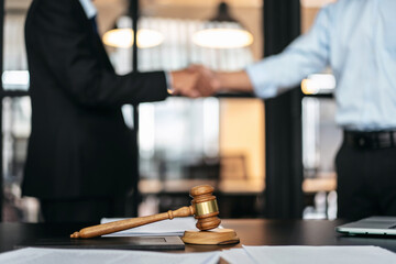 Handshake after good cooperation, Two people shaking hands after discussing contract agreement on front a judge's gavel - 775184106