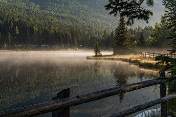 Nebel schwebt über dem Prebersee in Österreich, die Bäume spiegeln sich im See