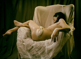 woman without clothes lying in an armchair on lace and tulle in a romantic attitude IV