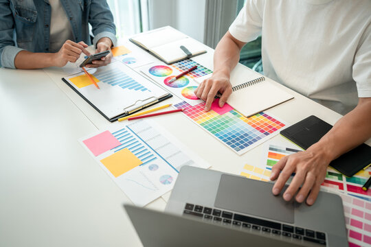 Two creative graphic designer team working on color selection and drawing on graphic tablet, Color swatch samples chart for selection coloring in inspiration to creativity at workplace