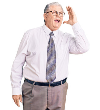 Senior grey-haired man wearing business clothes shouting and screaming loud to side with hand on mouth. communication concept.