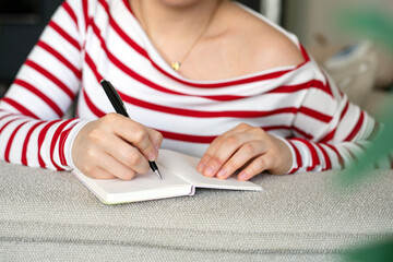 Close-up woman hand writes in notebook