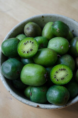 Kiwi berries (hardy kiwi) in a bowl, with fruit cross-sections shown