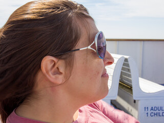 A woman wearing sunglasses and a pink shirt is sitting on a bench
