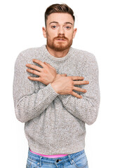Young redhead man wearing casual winter sweater shaking and freezing for winter cold with sad and shock expression on face
