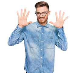 Young redhead man wearing casual denim shirt showing and pointing up with fingers number ten while smiling confident and happy.