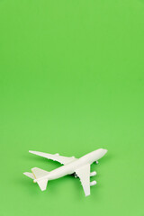 Travel concept. Isolated white miniature commercial airplane on green background. Vertical composition