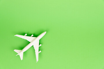 Top view composition of miniature commercial airplane isolated on green background. Summer vacation travel concept.