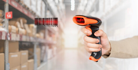 A person is holding a barcode scanner in a warehouse. A person is holding a barcode scanner and the barcode is red.