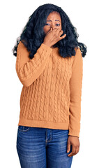 Beautiful african american woman wearing casual  sweater smelling something stinky and disgusting, intolerable smell, holding breath with fingers on nose. bad smell