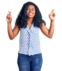 Beautiful african american woman wearing casual summer shirt gesturing finger crossed smiling with hope and eyes closed. luck and superstitious concept.