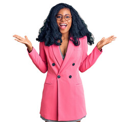 Beautiful african american woman wearing business jacket and glasses celebrating victory with happy smile and winner expression with raised hands