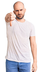 Young handsome man wearing casual t shirt looking unhappy and angry showing rejection and negative with thumbs down gesture. bad expression.