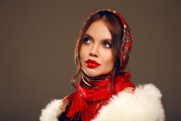 Fashion woman portrait with traditional red headscarf. Russian beauty girl model with red lips makeup isolated on studio background.