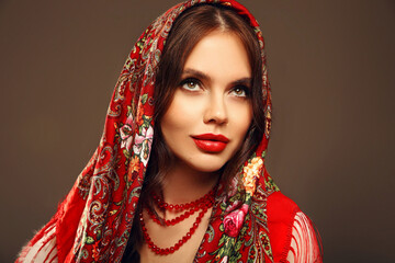 Russian girl Matryoshka style. Fashion woman portrait with traditional red headscarf. Beauty girl model with red lips makeup isolated on studio background. - 775209975