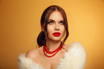 Portrait of beautiful young girl with red lips and bare shoulders in white furl coat on yellow studio background.  Alluring woman with hope looking up. skincare and wellness concept.