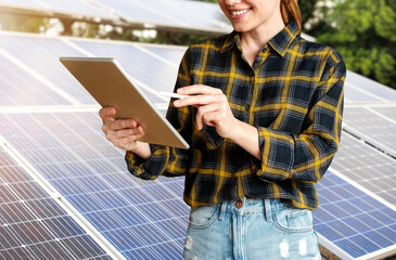 Female engineer checks the technical condition of solar panels using a digital tablet.