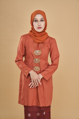 Beautiful female model wearing classic orange color  kebaya with hijab, an Asian traditional dress...