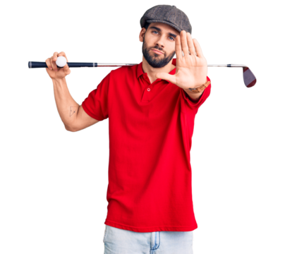 Young handsome man with beard playing golf holding club and ball with open hand doing stop sign with serious and confident expression, defense gesture