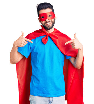 Young handsome man with beard wearing super hero costume looking confident with smile on face, pointing oneself with fingers proud and happy.