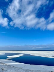 Frozen sea coast, ice at the sea, sea horizon, sky reflection on the water surface, natural colors