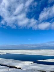Fototapeta premium Frozen sea coast, ice at the sea, sea horizon, sky reflection on the water surface, natural colors