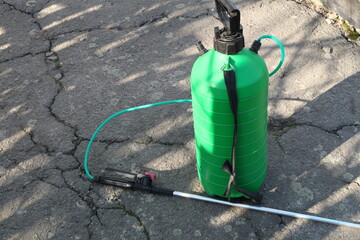 Green plastic balloon for tree treatment. In the yard, there is a tank with a solution for spraying...