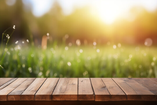 Empty wooden planks or tabletop in front of a blurred bokeh lush grass nature environment with water drops and minimalist background a product display background or wallpaper concept with front-lighti
