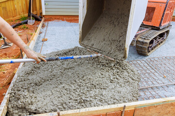 Self dumping track concrete buggy is used to pour wet cement into framework during foundation construction - Powered by Adobe