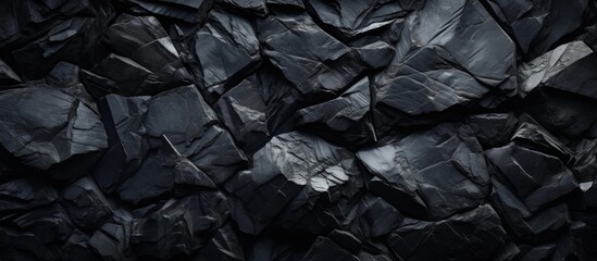 Black rocks stacked closely together are highlighted by a bright white light, creating a striking...